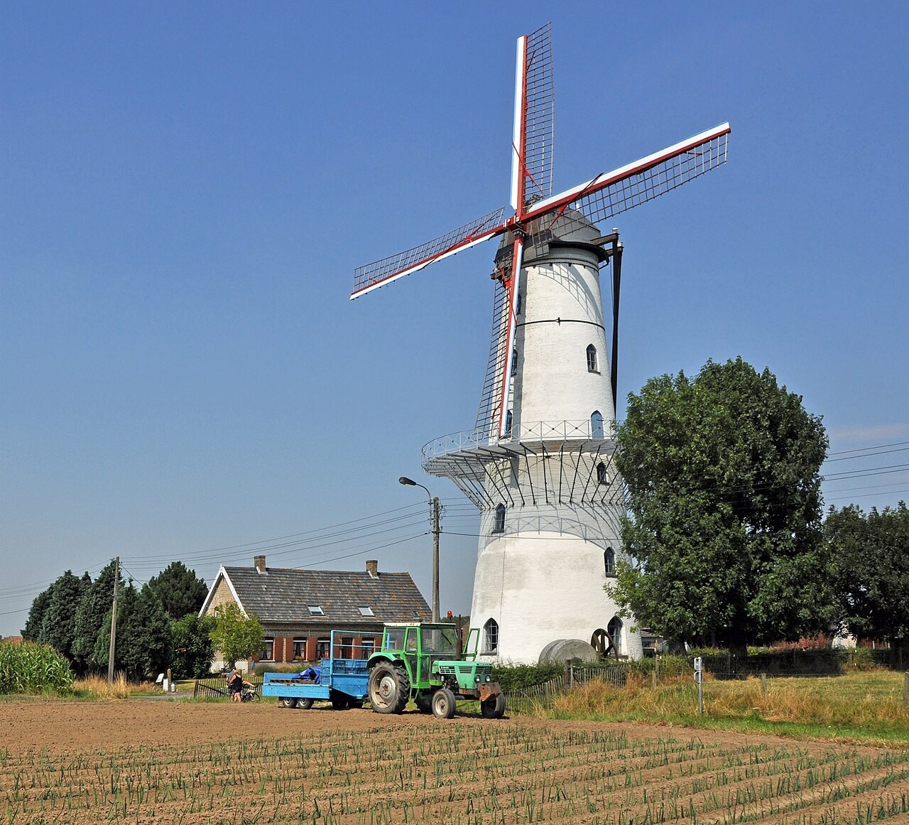 De hoge stenen Couchezmolen in Zarren met de wieken boven het omliggende terrein.