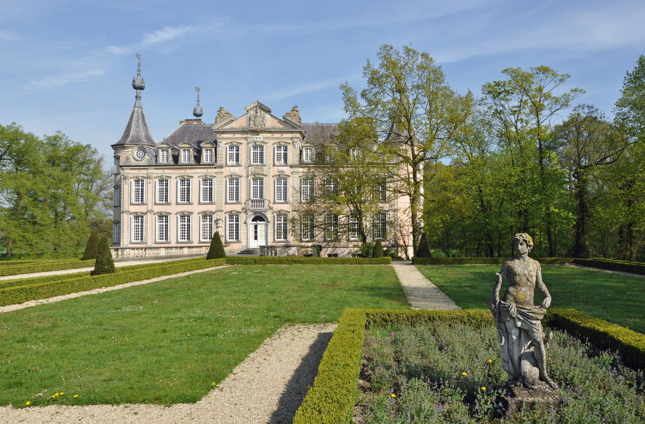 Het roze Kasteel van Poeke achter de watergracht, met de tuin op de voorgrond.