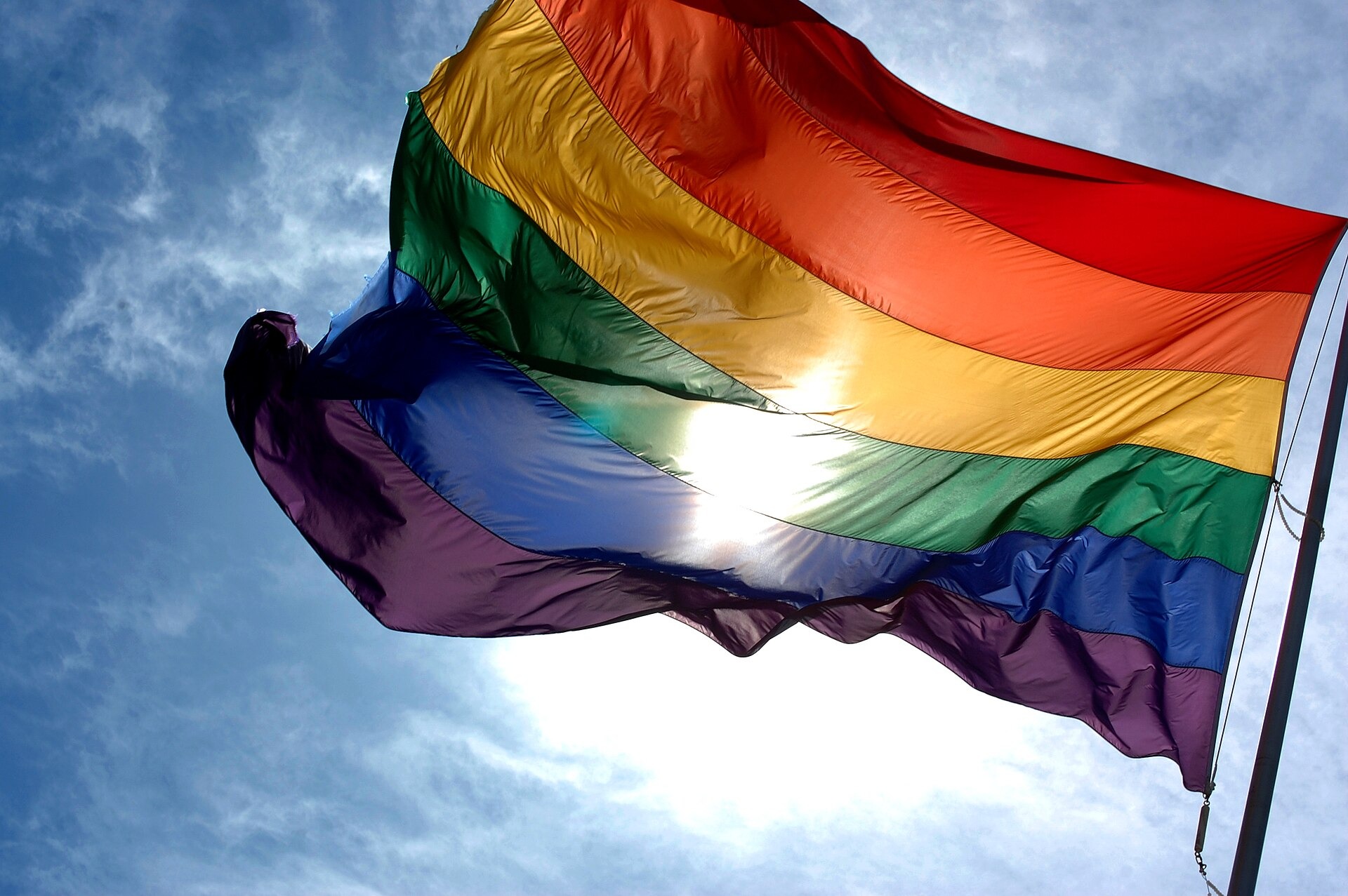 Regenboogvlag die wappert tegen een blauwe lucht.