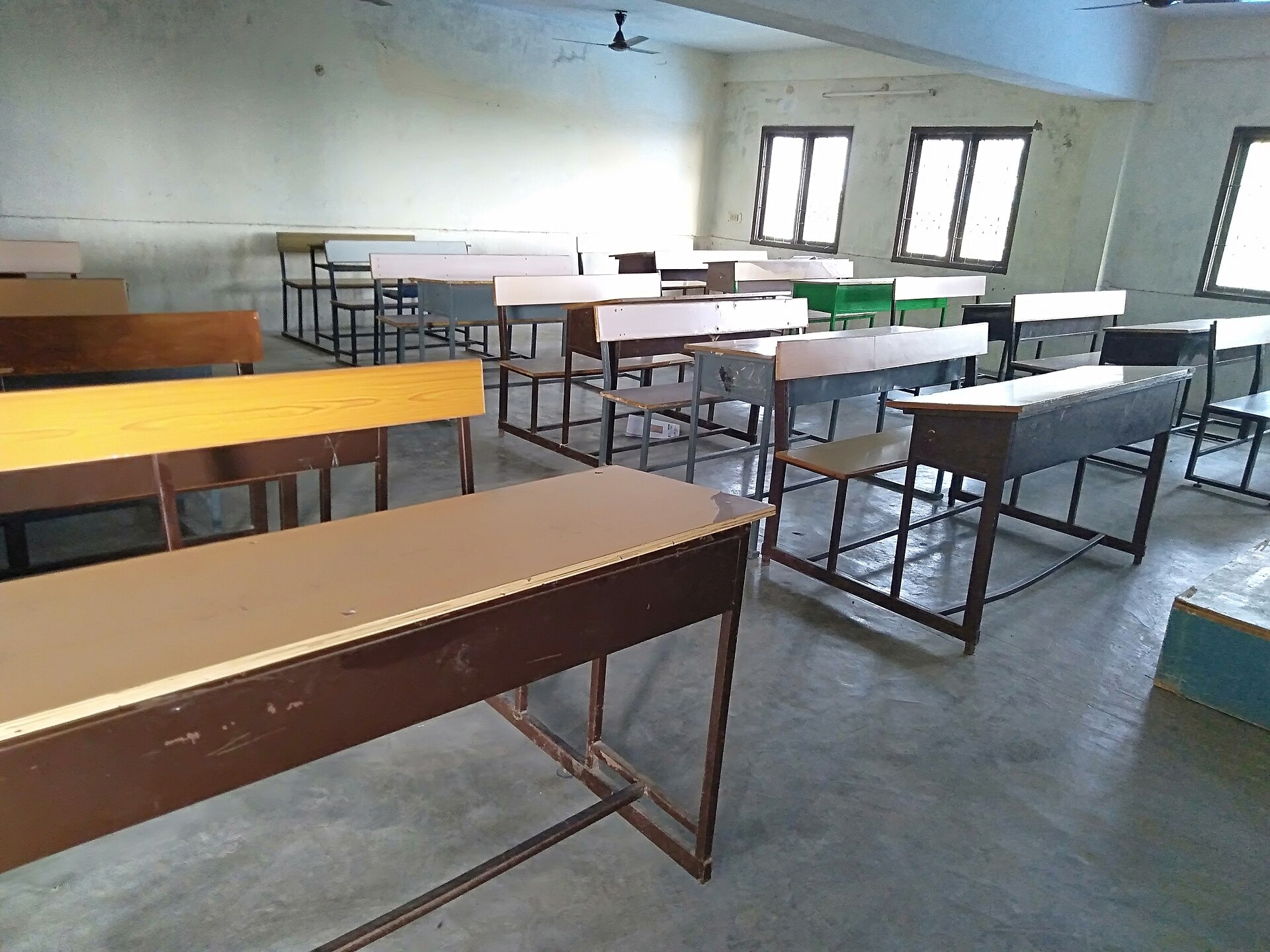 Leeg klaslokaal met schoolbanken en een schoolbord.