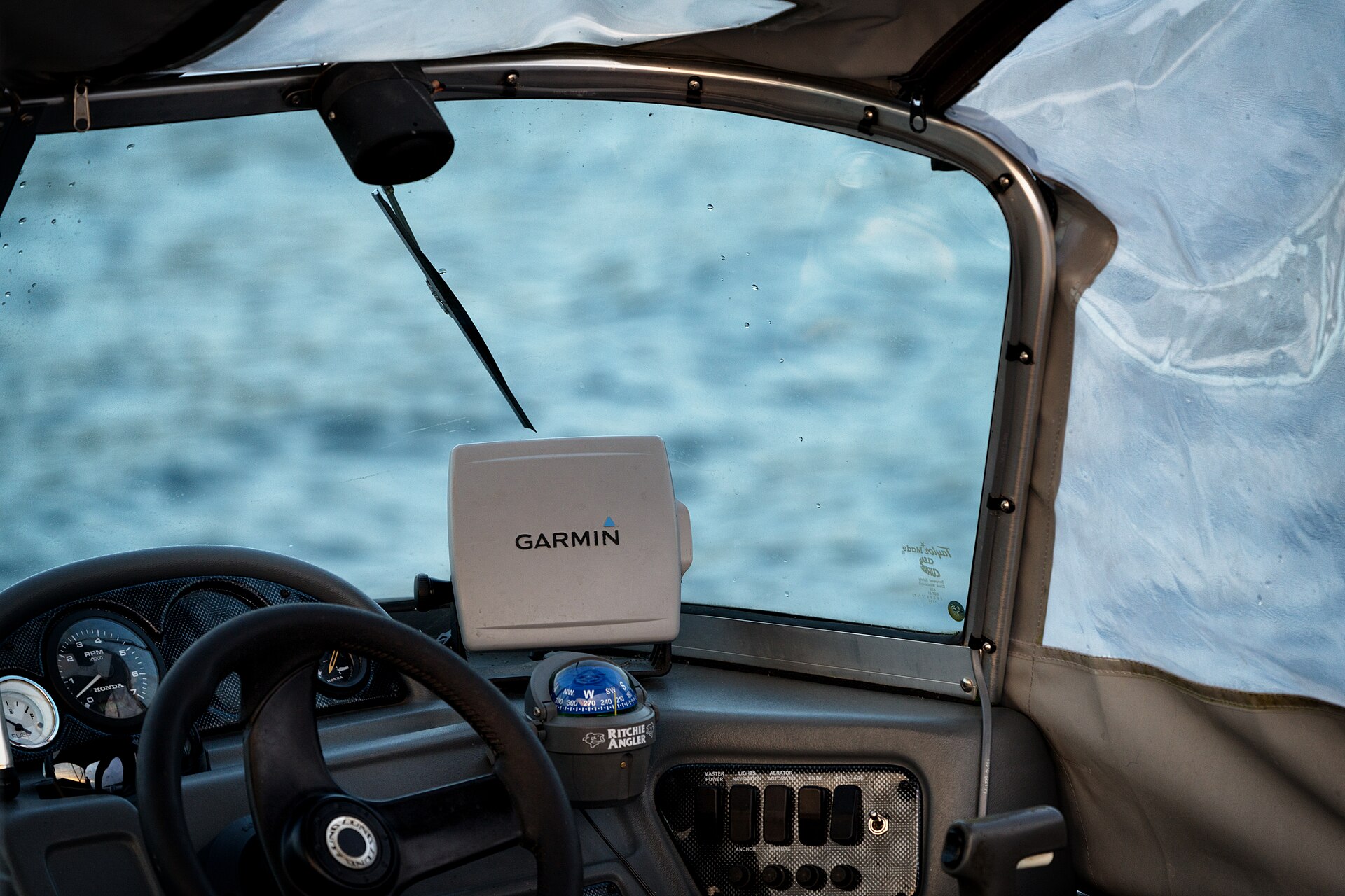 Een gps-ontvanger met het merk Garmin is gemonteerd bij de stuurstand van een boot.