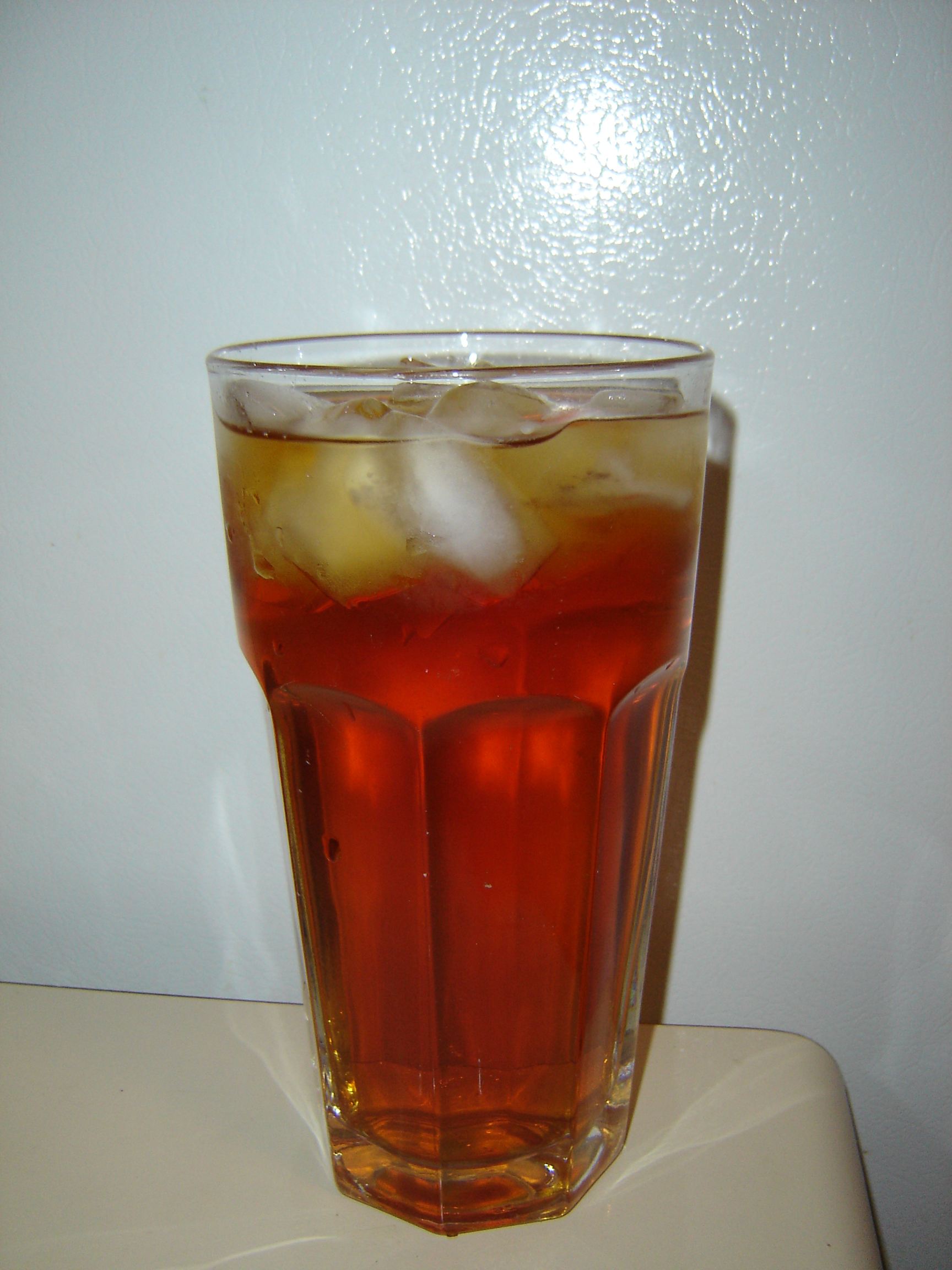 IJsblokjes drijven bovenin een glas bruine ijsthee.