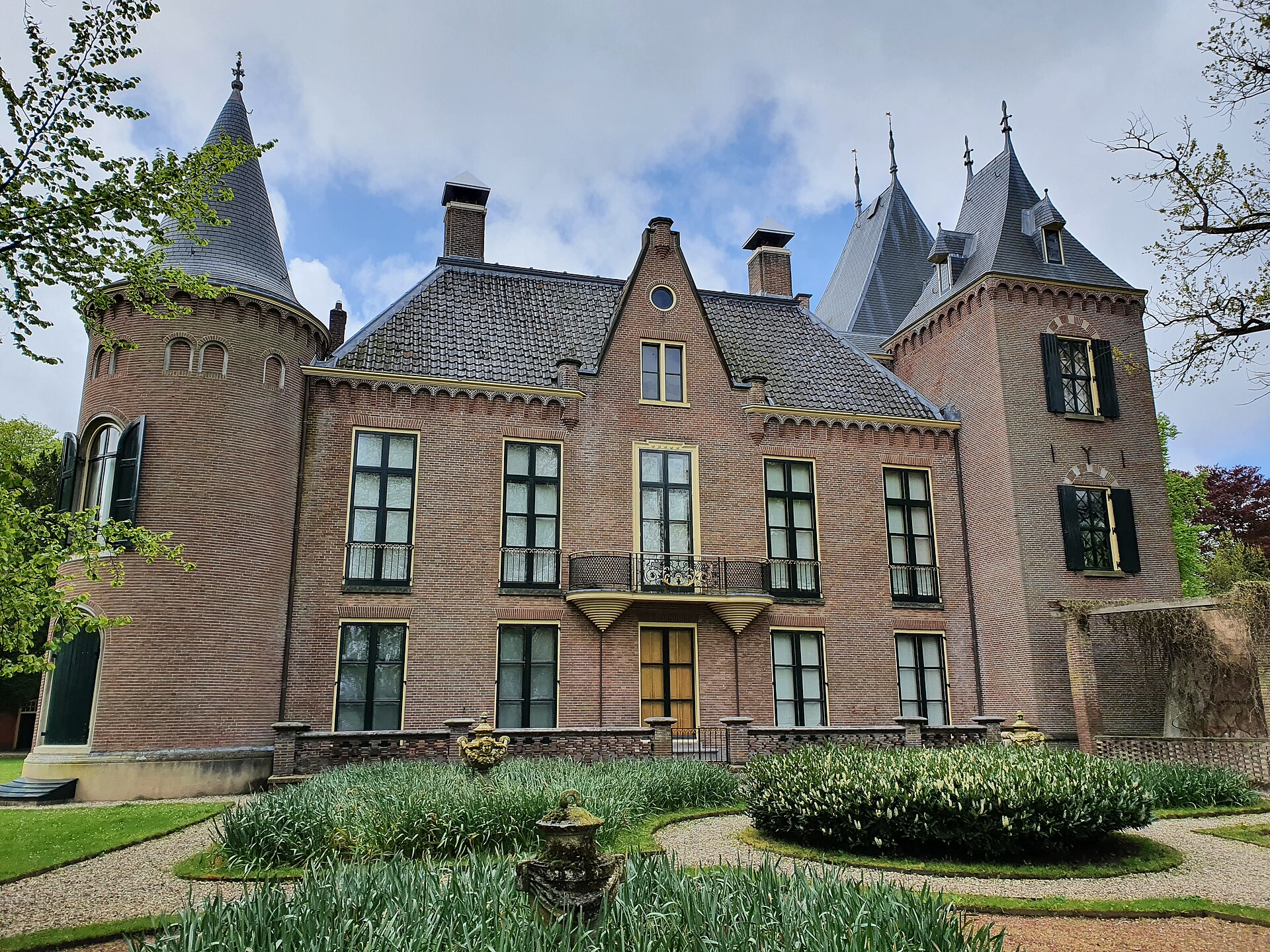 De bakstenen voorgevel met torens van Kasteel Keukenhof in Lisse, met een tuin op de voorgrond.