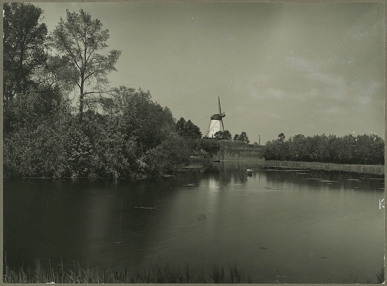 Zwart-wit archiefbeeld van water, vestingwal en molen in Willemstad. Illustratief detail van de vesting; de volledige stervorm is hier niet zichtbaar.