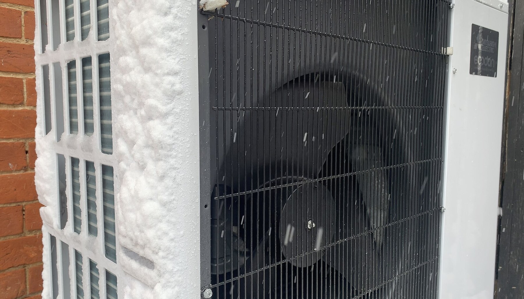 Buitenunit van een warmtepomp met sneeuw in de omgeving.