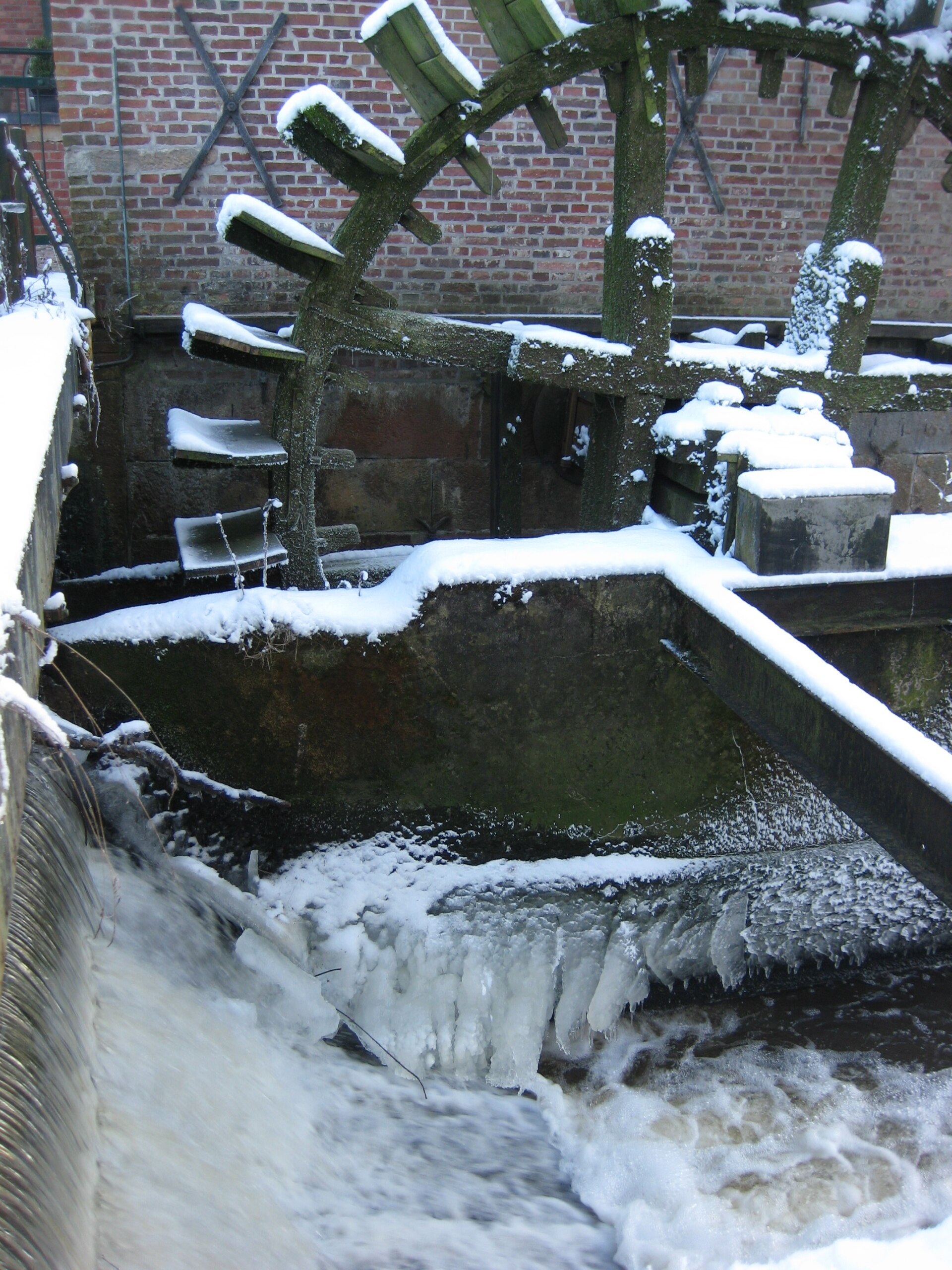 Sneeuw en ijs rond het waterrad van de Berenschot-watermolen bij Winterswijk.