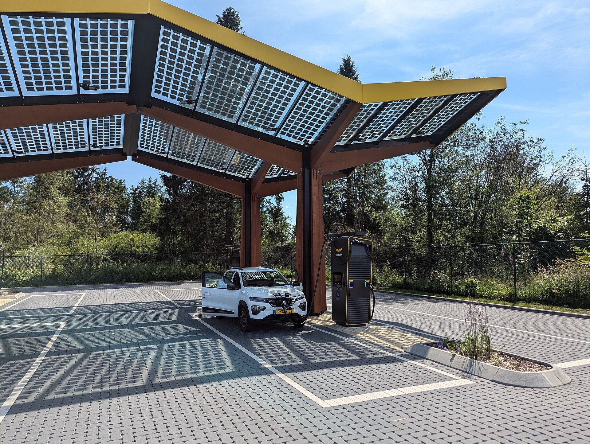 Een witte Dacia Spring staat bij een Fastned-snellaadstation in België.