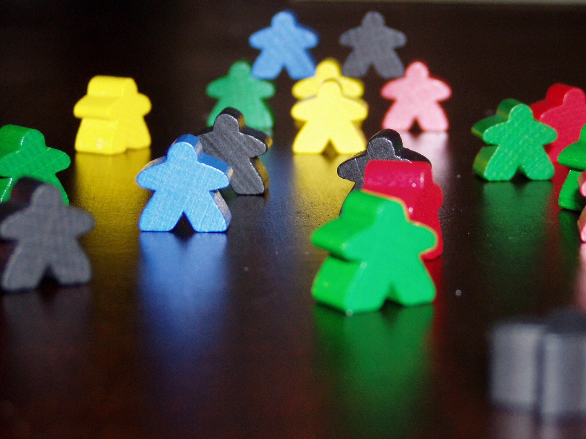 Gekleurde houten meeples voor Carcassonne op een donkere ondergrond.