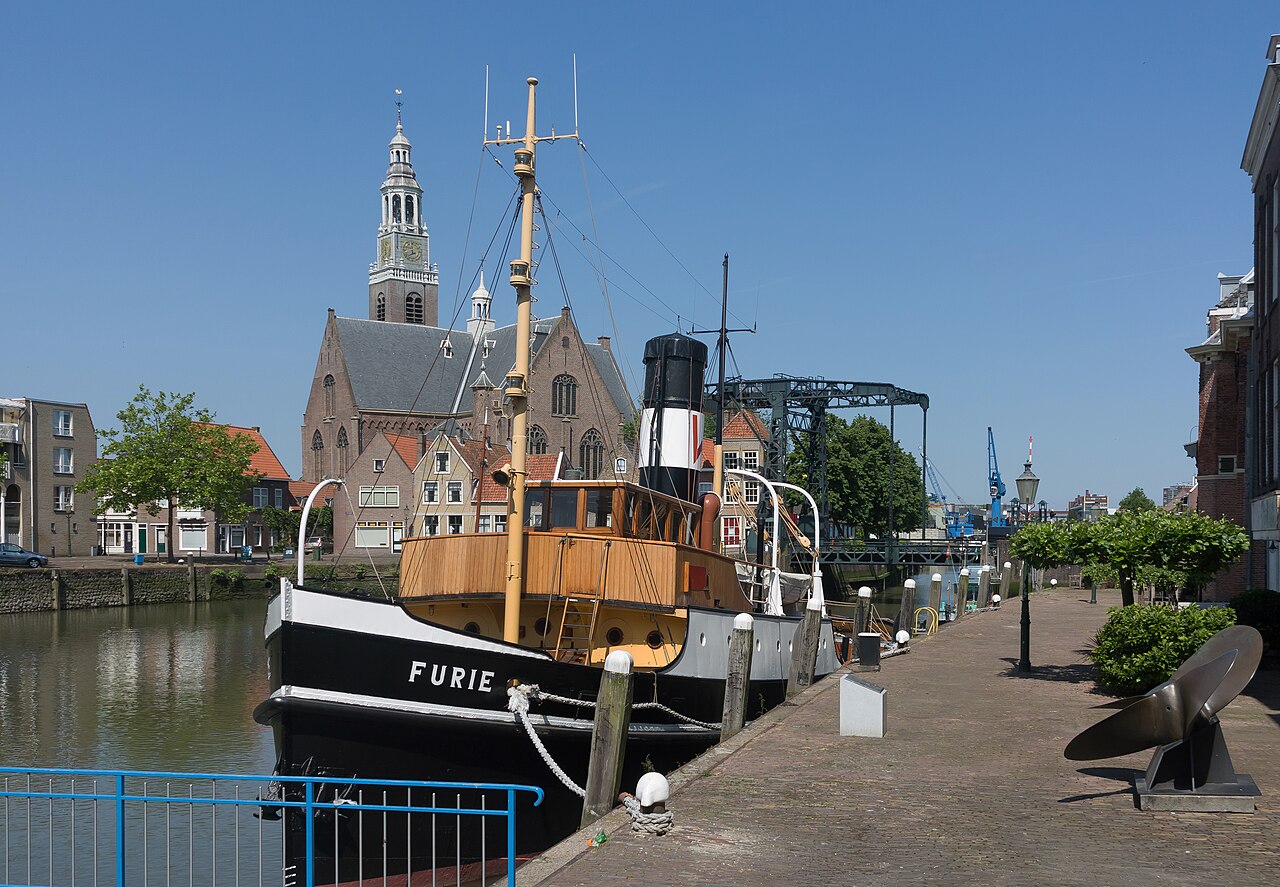 De stoomsleepboot Furie aan de kade, met de Groote Kerk in Maassluis op de achtergrond.